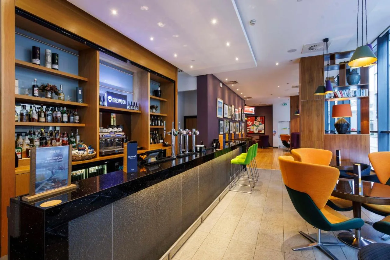 A bar with yellow chairs inside RBG Bar & Grill at Park Inn Aberdeen